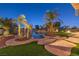 A backyard with a freeform pool and mature landscaping including palm trees under a twilight sky at 2780 El Camino Rd, Las Vegas, NV 89146