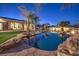 A backyard with a freeform pool, rock features, and mature landscaping including palm trees at 2780 El Camino Rd, Las Vegas, NV 89146