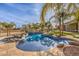 Inviting in-ground pool with rock accents, spa, and swaying palm trees creating a private escape at 2780 El Camino Rd, Las Vegas, NV 89146