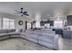 Spacious living room with a large gray sectional sofa, ceiling fan, and an open layout to the kitchen at 2929 Salado Creek Ave, North Las Vegas, NV 89081