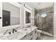 Modern bathroom with double vanity, marble countertops, illuminated mirrors, and glass shower with a unique window at 366 Rancho La Costa St, Las Vegas, NV 89138