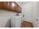 Functional laundry room equipped with modern washer and dryer, wooden cabinets, and a white door at 4217 Box Canyon Falls Ave, North Las Vegas, NV 89085