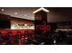 Lounge with illuminated bar, dark accents, red lighting, modern furniture, and ample seating at 4381 W Flamingo Rd # 1504, Las Vegas, NV 89103