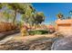 Lush backyard featuring mature trees, a stone retaining wall, and circular grassy area for outdoor enjoyment at 4775 N Grand Canyon Dr, Las Vegas, NV 89129