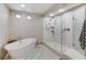 Bright bathroom featuring a soaking tub and glass-enclosed shower with marble tile and modern fixtures at 6618 Tangled Vines Ave, Las Vegas, NV 89139