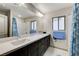 Bathroom featuring a double vanity with dark wood cabinets, marble countertop, and large mirror at 6618 Tangled Vines Ave, Las Vegas, NV 89139