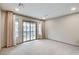 Bright bedroom with a sliding glass door to a balcony and neutral colored walls and carpet at 6618 Tangled Vines Ave, Las Vegas, NV 89139