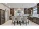 Modern kitchen features dark wood cabinetry, stainless steel appliances, and a center island with seating at 6618 Tangled Vines Ave, Las Vegas, NV 89139