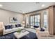 Staged living room with white furniture, blue accents, and a sliding glass door to a patio at 6618 Tangled Vines Ave, Las Vegas, NV 89139