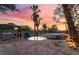 Wide angle backyard view featuring an outdoor kitchen, above ground pool, multiple mature palms and a colorful sunset at 711 Sari Dr, Las Vegas, NV 89110
