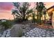 Wide backyard view of a mature landscaped yard with seating and barbeque under a colorful sunset at 711 Sari Dr, Las Vegas, NV 89110
