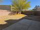The backyard features a tree with yellow flowers, a rock feature and patio area at 734 Rusty Spur Dr, Henderson, NV 89014