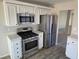 Modern kitchen with stainless steel appliances, white cabinetry and views into an adjacent living space at 734 Rusty Spur Dr, Henderson, NV 89014