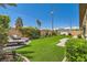 Expansive backyard with lush artificial turf, lounge chairs, mature landscaping, and a serene atmosphere at 7473 Deschutes Cir, Las Vegas, NV 89129
