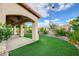 Charming backyard featuring artificial turf, a covered patio, and a well-maintained garden at 7709 Sierra Paseo Ln, Las Vegas, NV 89128