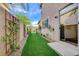 A side yard is shown featuring a grassy area with decorative vines and a gate to the backyard at 7709 Sierra Paseo Ln, Las Vegas, NV 89128