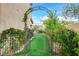 Tranquil backyard featuring a metal garden gate covered in flowering vines at 7709 Sierra Paseo Ln, Las Vegas, NV 89128