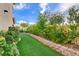 Lush backyard with a brick retaining wall, artificial turf, and colorful flowering plants at 7709 Sierra Paseo Ln, Las Vegas, NV 89128
