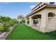 View of the home's backyard featuring a covered patio, artificial turf, and lush landscaping at 7709 Sierra Paseo Ln, Las Vegas, NV 89128