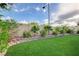 Well-kept artificial turf bordered by brick edging and lush landscaping along a privacy wall at 7709 Sierra Paseo Ln, Las Vegas, NV 89128