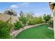 Manicured backyard with lush plants, green artificial turf, and a tidy retaining wall at 7709 Sierra Paseo Ln, Las Vegas, NV 89128