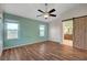 Spacious bedroom with wood floors, two windows, a ceiling fan, and barn door to bathroom at 7709 Sierra Paseo Ln, Las Vegas, NV 89128