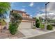 Two-story stucco home featuring a tile roof and a two-car garage on a tree lined street at 7709 Sierra Paseo Ln, Las Vegas, NV 89128