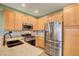Well-lit kitchen featuring wood cabinets, stone countertops, and stainless steel appliances at 7709 Sierra Paseo Ln, Las Vegas, NV 89128