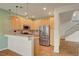Well-lit kitchen featuring stainless steel appliances, wood cabinets, and a breakfast bar overlooking the staircase at 7709 Sierra Paseo Ln, Las Vegas, NV 89128
