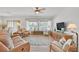 Bright and airy living room with hardwood floors, neutral paint, ceiling fan, and large windows at 7908 House Sparrow St, North Las Vegas, NV 89084