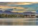 Scenic lake view with community recreational facilities, mountains in the distance, and stunning sunset at 8228 Lauderdale Ct, Las Vegas, NV 89128