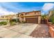 Exterior shot of a two-story home with desert landscaping, tile roof, an attached two-car garage and a brick driveway at 905 Possum Hill St, Henderson, NV 89014