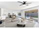 Bright open-concept living room with a ceiling fan, sliding glass door, and view of the backyard pool at 9541 Summersweet Ct, Las Vegas, NV 89123