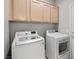 A laundry room with a washing machine and a dryer with wooden cabinets above at 9624 Twelve Pins Dr, Las Vegas, NV 89129