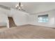 Bright living room with a staircase, large window, and modern chandelier at 10508 Waking Cloud Ave, Las Vegas, NV 89129