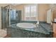 Elegant bathroom with a large tub, glass-enclosed shower, and decorative tile work at 11275 Gammila Dr, Las Vegas, NV 89141