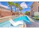 A luxurious pool with a built-in lounge chair and lush landscaping creates a serene backyard oasis at 11275 Gammila Dr, Las Vegas, NV 89141