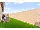 Another view of the backyard's side wall, grass, and AC unit at 12648 Heritage Bend Dr, Las Vegas, NV 89138