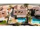 Overhead view of a kidney-shaped pool, covered patio, desert landscaping, and nearby neighboring pools at 1528 Tonada Way, Las Vegas, NV 89117