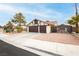 View of a two-car garage and fenced in front yard with desert landscaping at 1528 Tonada Way, Las Vegas, NV 89117