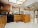 Functional kitchen with wood cabinets, black appliances, and a view of the backyard pool area at 1528 Tonada Way, Las Vegas, NV 89117