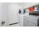 Bright laundry room with washer, dryer, storage shelves and door at 1528 Tonada Way, Las Vegas, NV 89117
