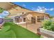 A backyard featuring a concrete patio, artificial grass, a shade sail, and an outbuilding at 1676 Divinity St, Las Vegas, NV 89142