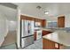 Well-equipped kitchen with stainless steel refrigerator, wooden cabinets, and durable tiled flooring at 1676 Divinity St, Las Vegas, NV 89142