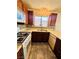 This kitchen features dark wood cabinets, tile backsplash, tile flooring, and stainless steel sink at 1676 Divinity St, Las Vegas, NV 89142