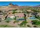 A high-angle shot of backyard pools, desert landscaping, and patios in a desert community against a mountain backdrop at 19 Contrada Fiore Dr, Henderson, NV 89011