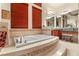 Bright bathroom featuring a soaking tub, vanity, and warm wood accents with neutral tile at 21 Avenida Sorrento, Henderson, NV 89011
