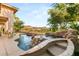 Resort-style pool featuring a serene waterfall, lush landscaping, and distant mountain views at 21 Avenida Sorrento, Henderson, NV 89011
