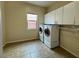 Bright laundry room featuring a stacked washer and dryer with ample storage and a tile floor at 2312 Indigo Island St, Henderson, NV 89044