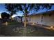 Front yard with rock landscaping, artificial turf, exterior lighting, and a charming facade at dusk at 419 National St, Henderson, NV 89015